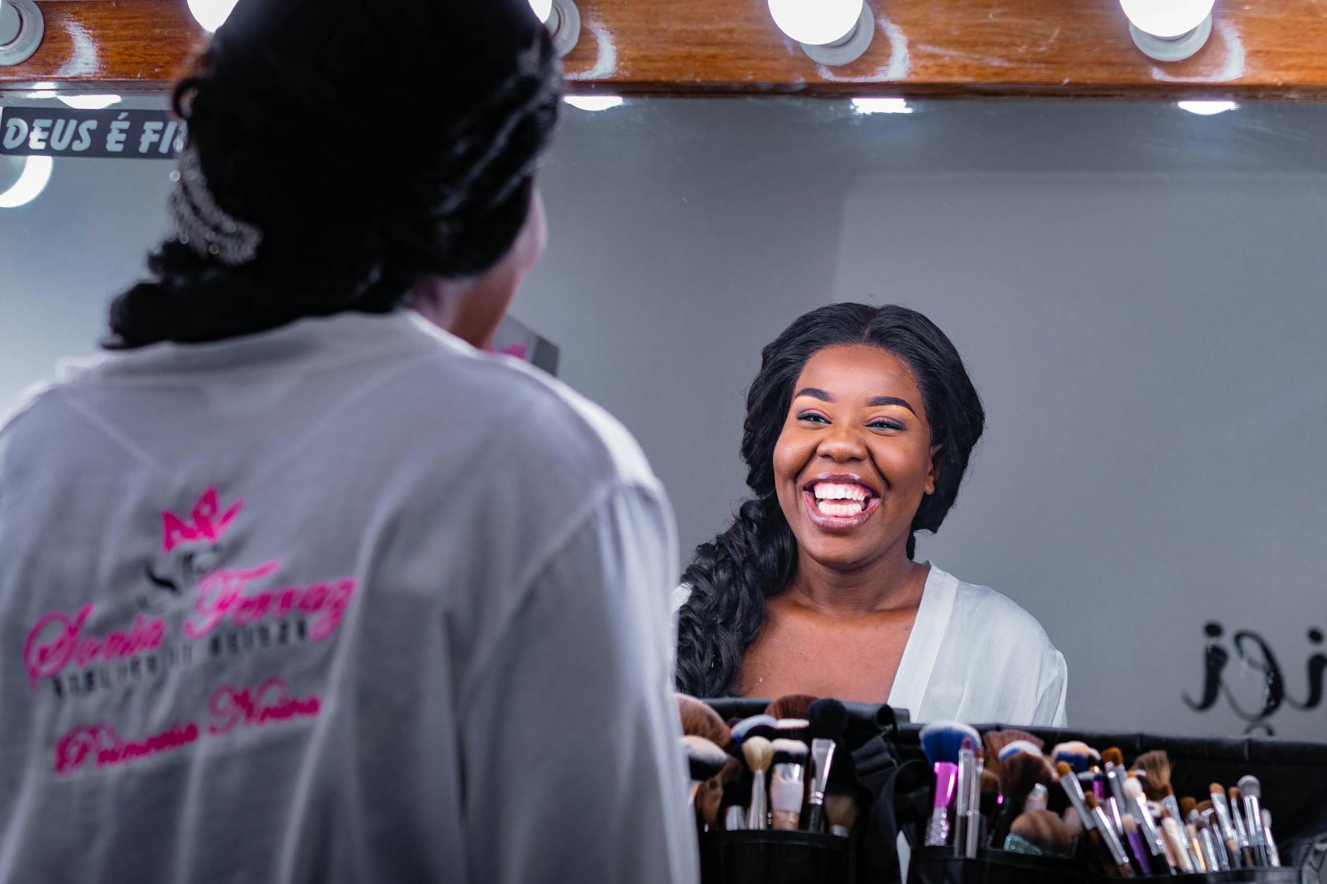 Czarna kobieta śmiejąca się do swojego odbicia w lustrze