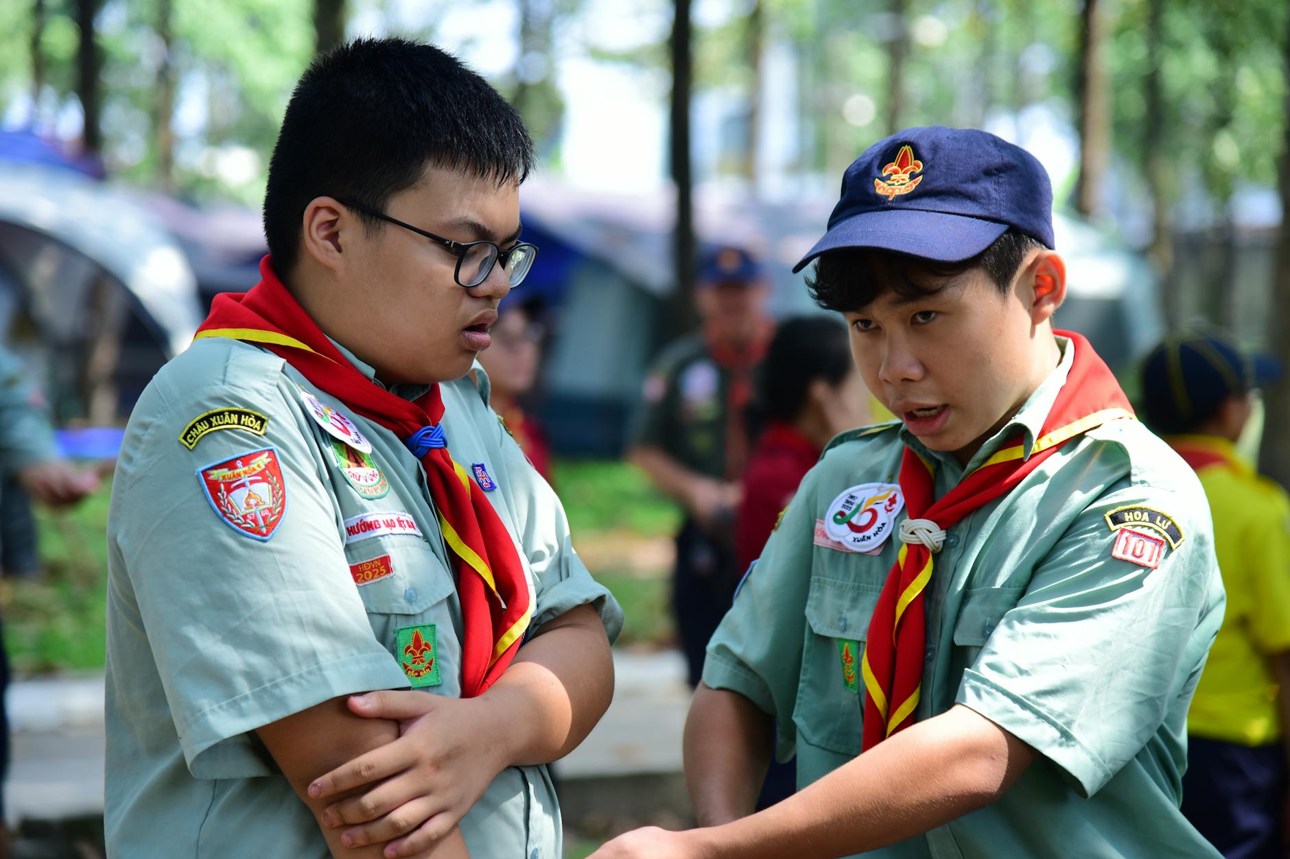 Dwóch harcerzy w mundurach rozmawia na biwaku w lesie