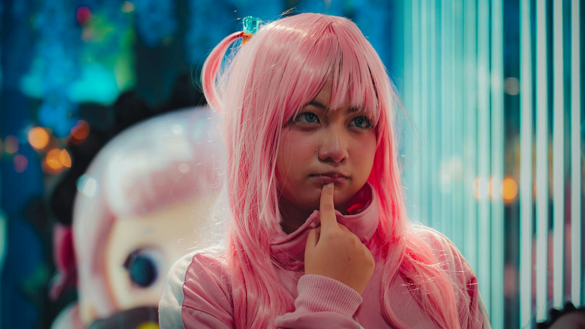 Dziewczyna w różowej peruce poprawia jej ułożenie w pomieszczeniu