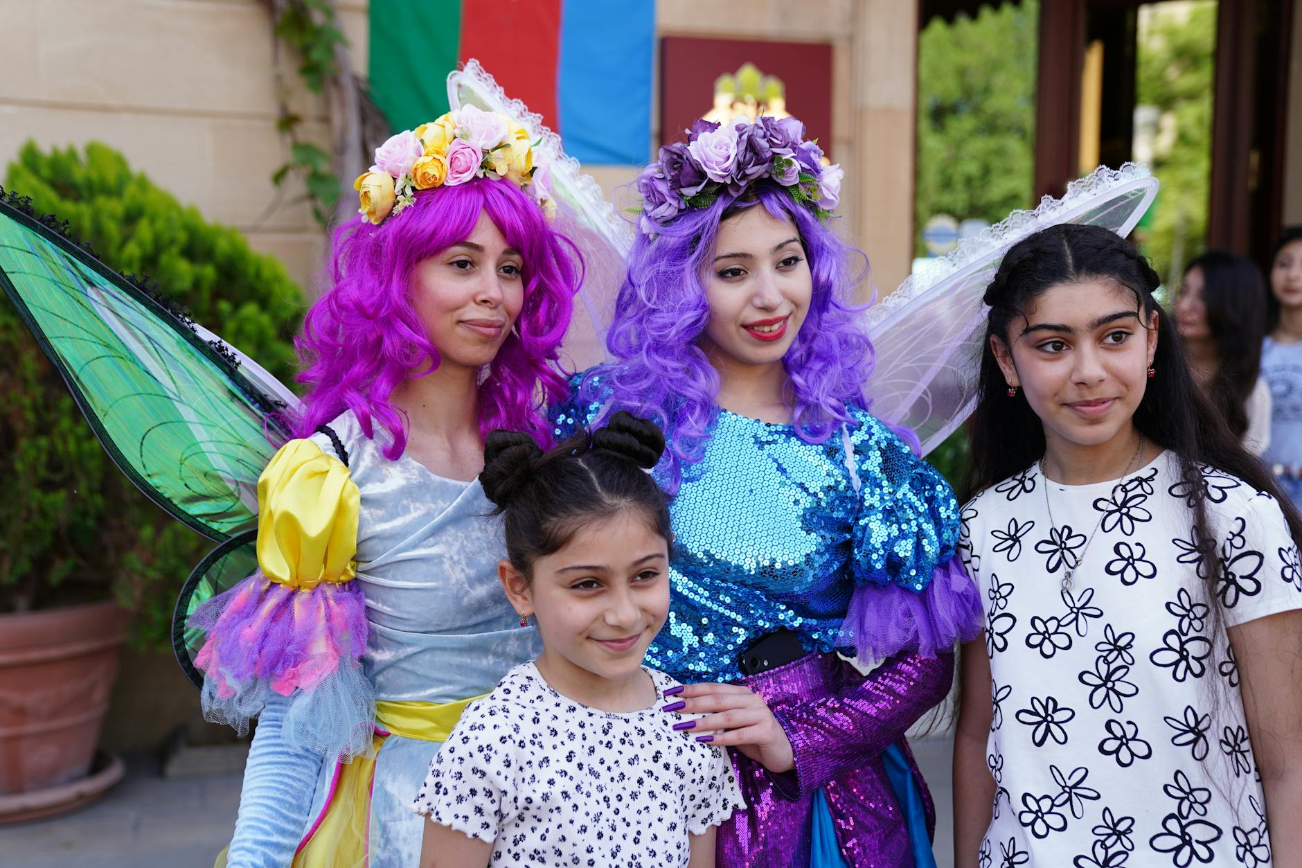 Dziewczynki z kobietami w barwnych strojach wróżek pozują na dworze