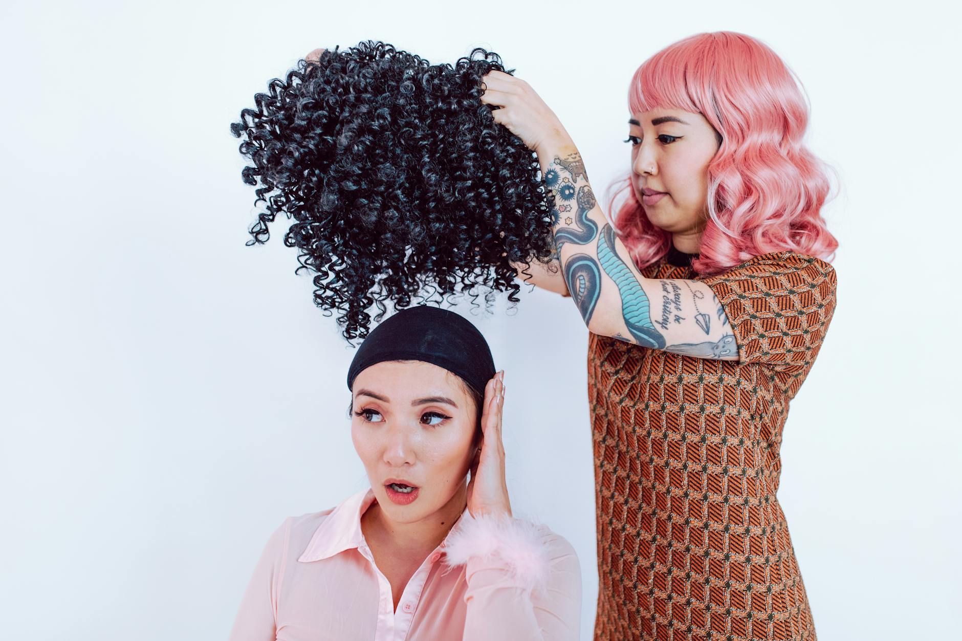 Fryzjerka dopasowuje kręconą perukę na głowie dorosłej kobiety