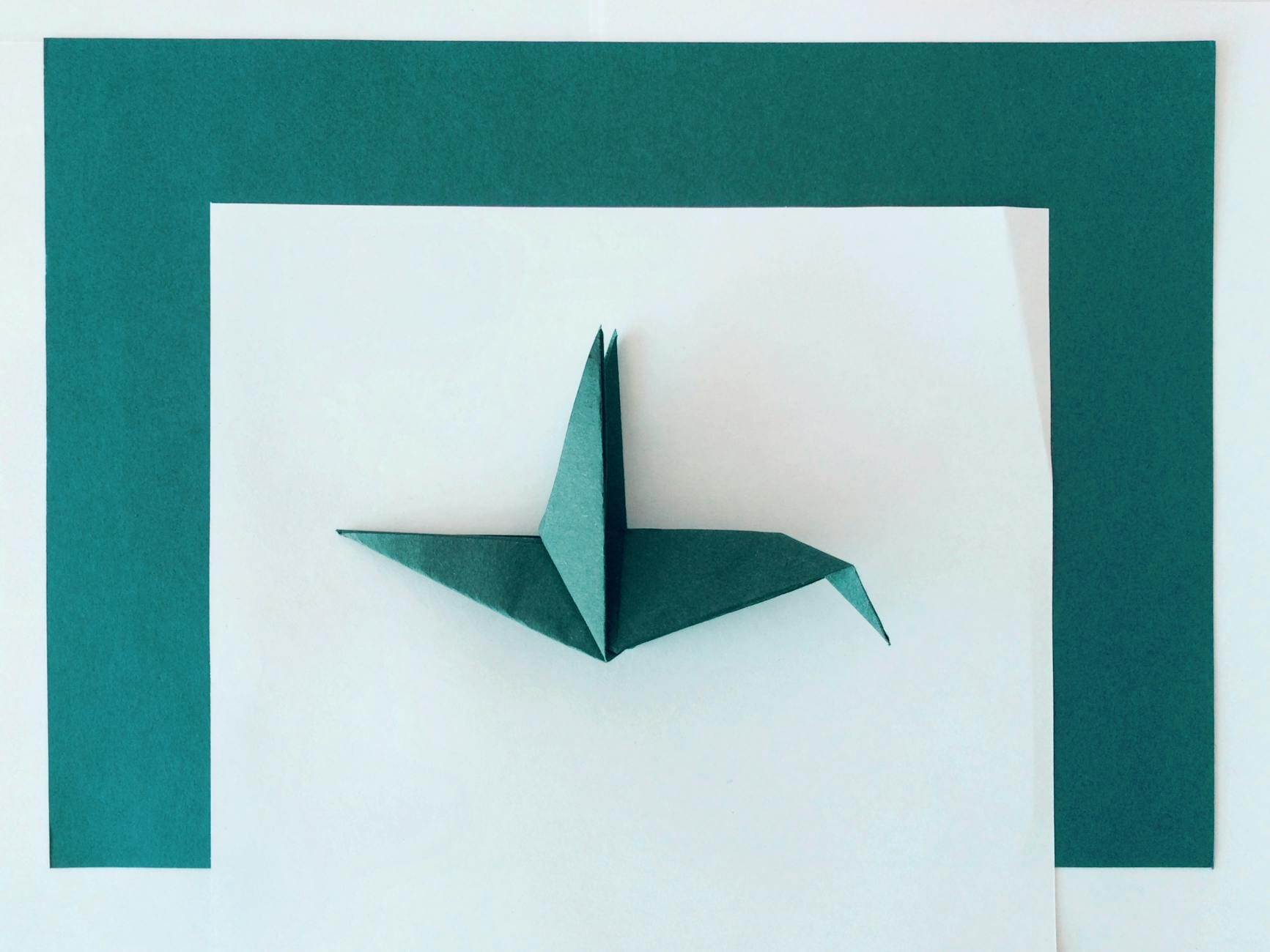 Jak zacząć origami modułowe – poradnik dla początkujących krok po kroku Turkusowy ptak origami na tle białego i turkusowego papieru