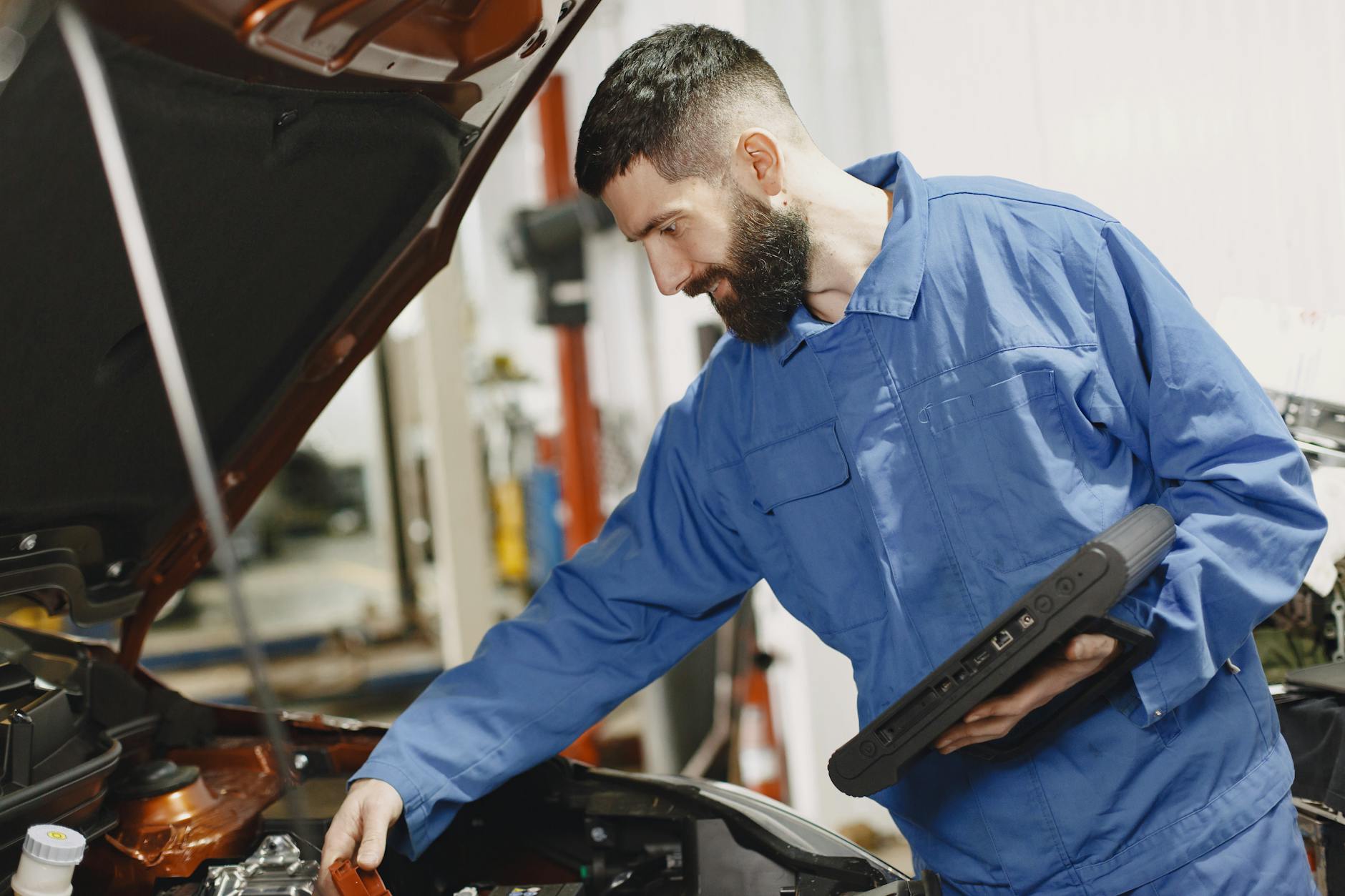 Jak samodzielnie sprawdzić używane BMW przed zakupem: praktyczna lista kontrolna dla kupującego Mechanik w niebieskim kombinezonie sprawdza silnik BMW w garażu