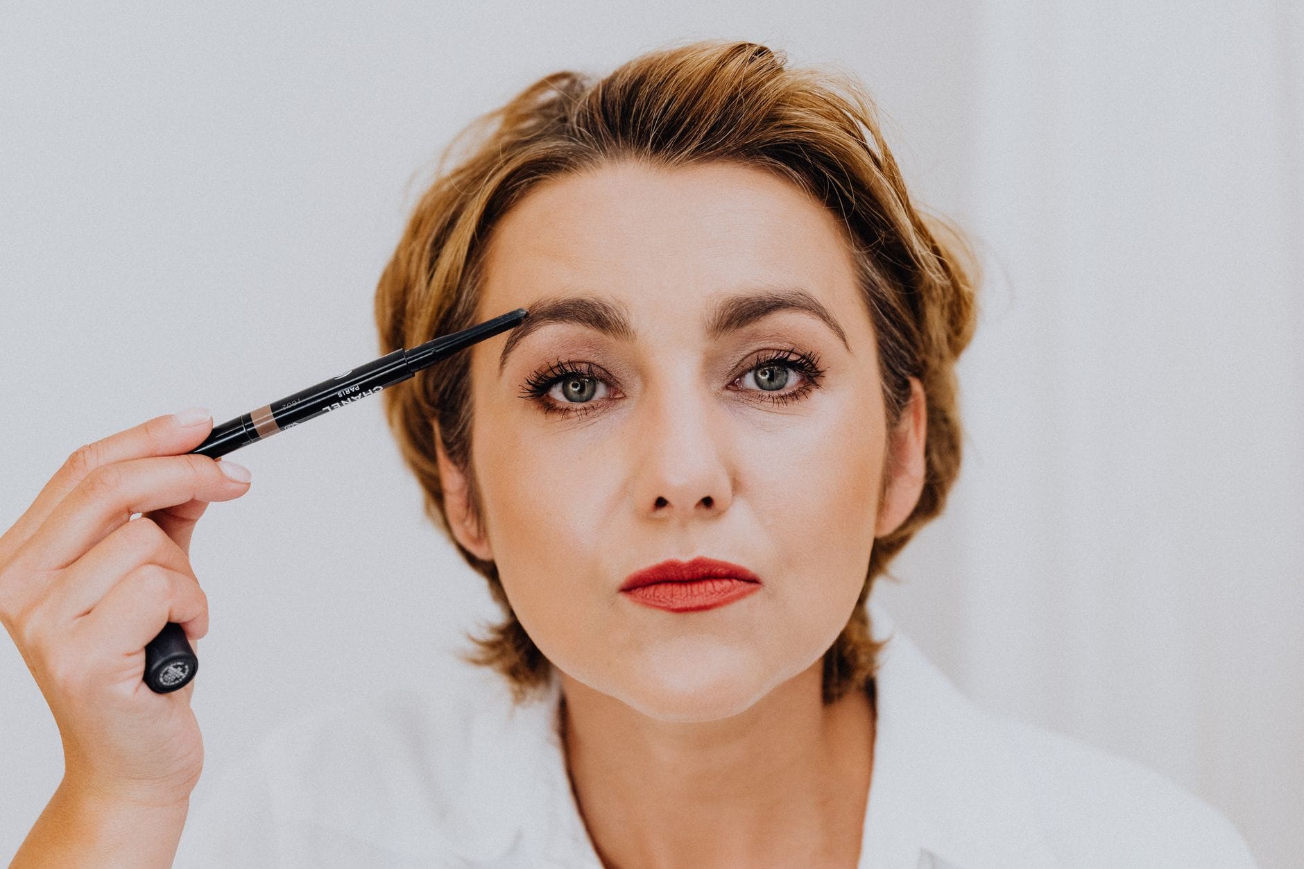 Kobieta z alopecją podkreślająca brwi kredką z bliska