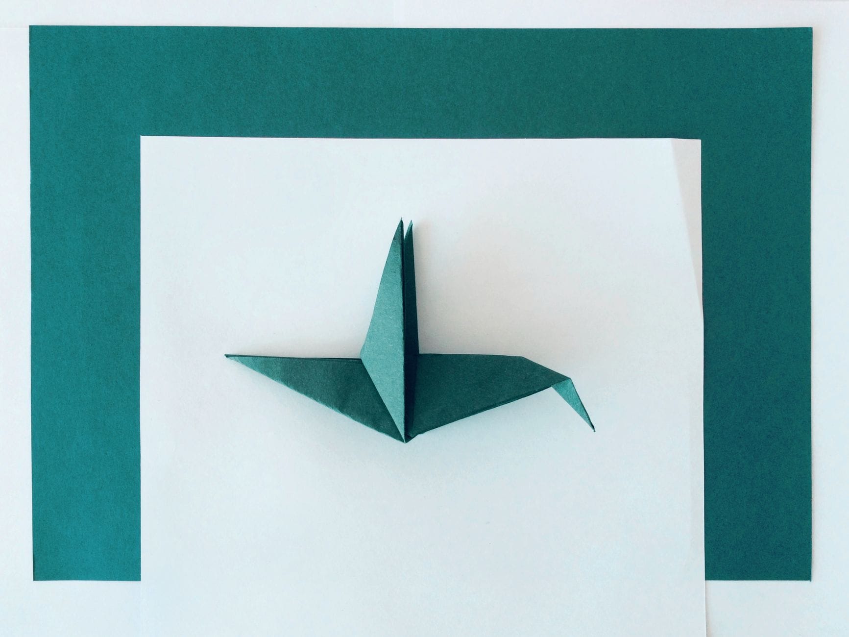 Jak zacząć przygodę z origami modułowym w domu – praktyczny poradnik dla początkujących Turkusowy ptak origami na tle białego i turkusowego papieru