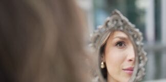 Topper z klipsami a cienkie włosy: kiedy mocowanie może być niewskazane Kobieta oglądająca włosy w ręcznym lusterku na świeżym powietrzu